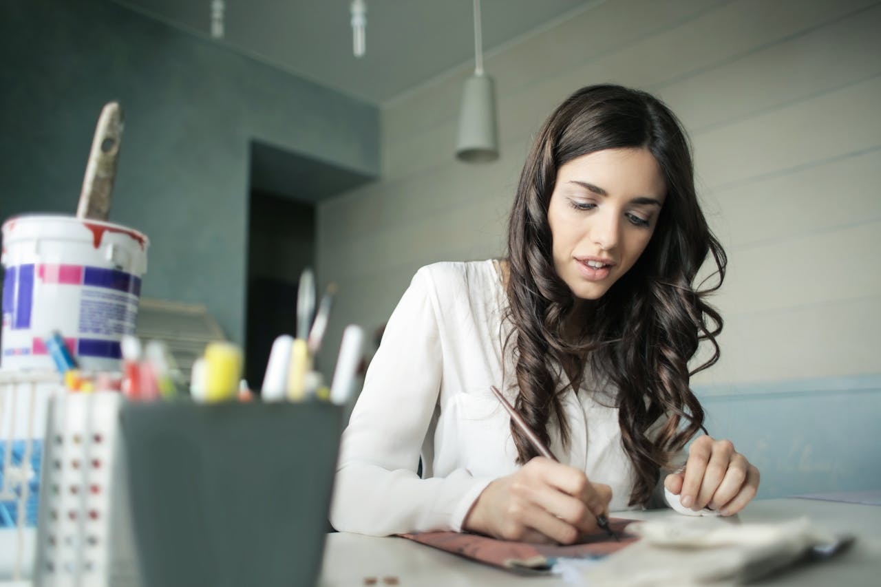 Young woman artist focused on painting at her workspace.